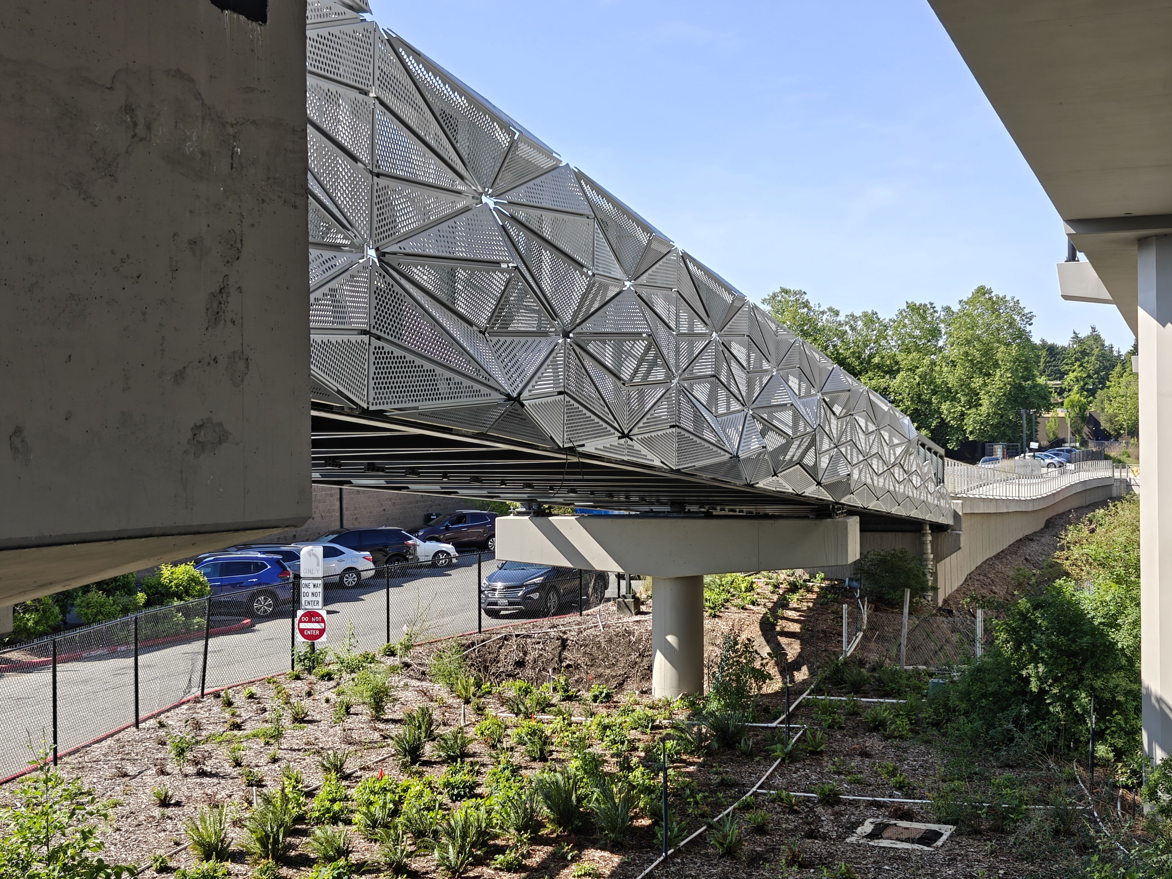 The photo shows one side of a pedestrian bridge, the railing clad in a perforated metal polygon design.